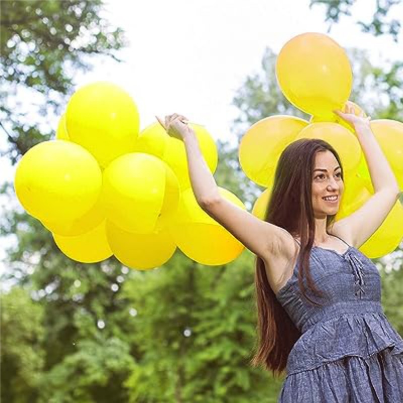 Flicka som håller Gula ballonger utomhus, skapar en glad och festlig atmosfär.